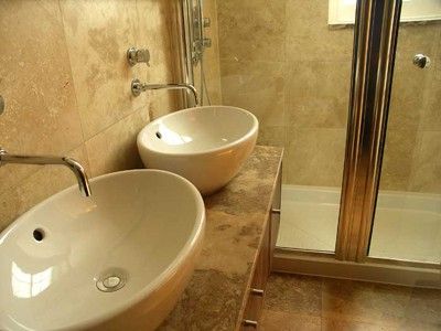 White his and her matching sinks in a brown stone bathroom serviced by Able Plumbing Repair Service, Inc. in Orange Park, FL