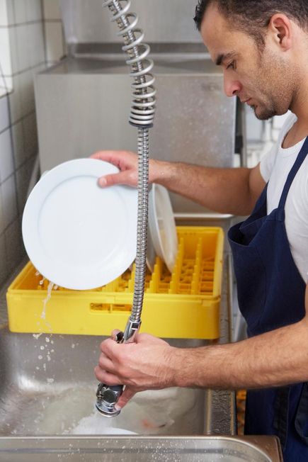 Male cleaning dishes in a professional kitchen sink serviced by Able Plumbing Repair Service, Inc. in Orange Park, FL